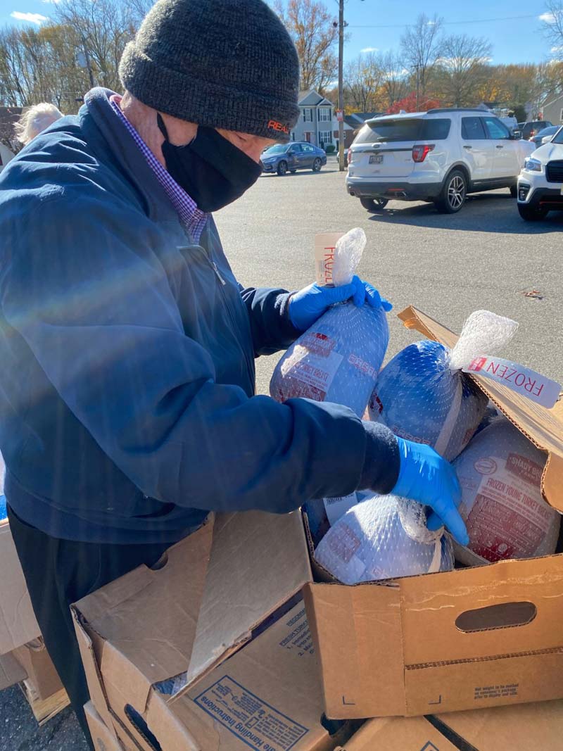 Man wearing facemask pulling frozen turkeys out of a box